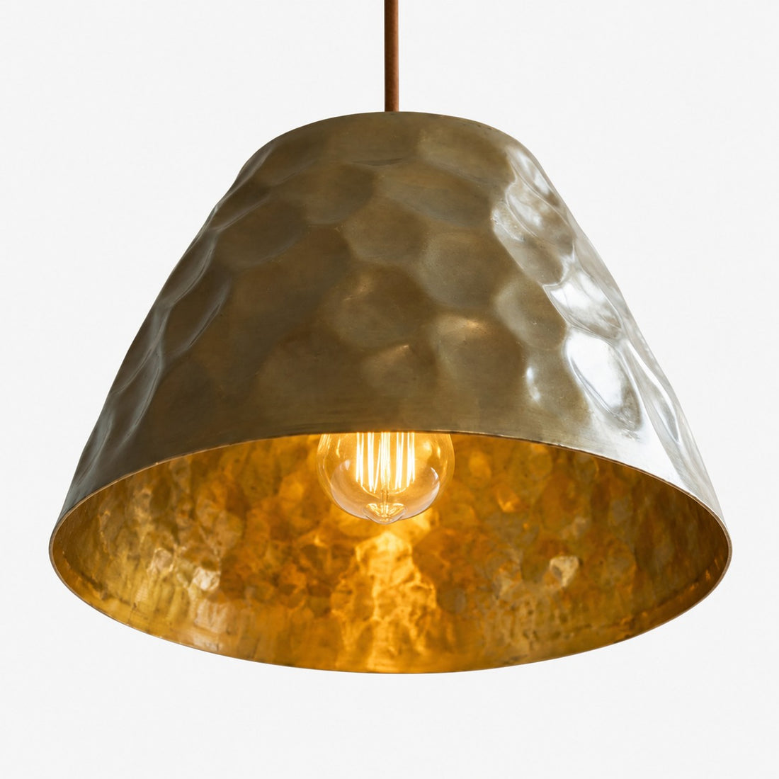 Close-up of the warm golden interior and bulb under the brass shade