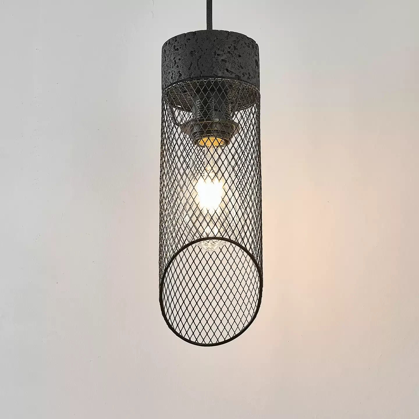 Black mesh pendant shade lit with a visible bulb inside