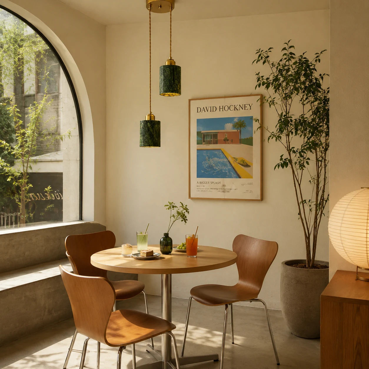 Two green jade cylinder pendant lights installed above a small dining table by an arched window