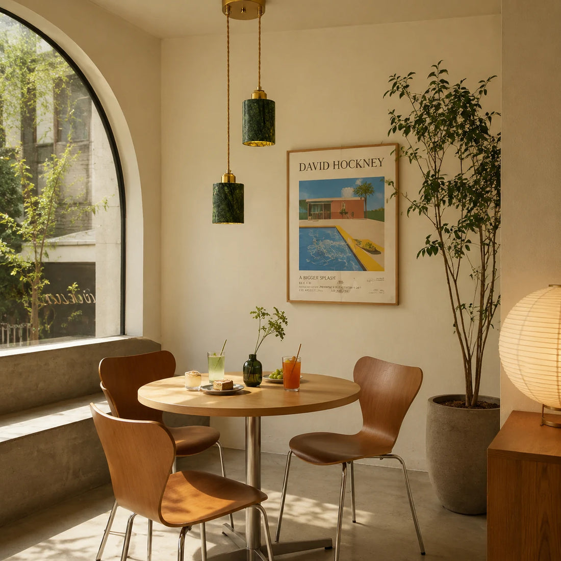 Two green jade cylinder pendant lights installed above a small dining table by an arched window