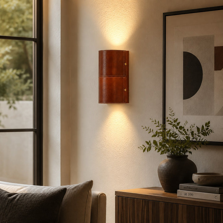 Brown leather wall sconce installed beside a sofa and window