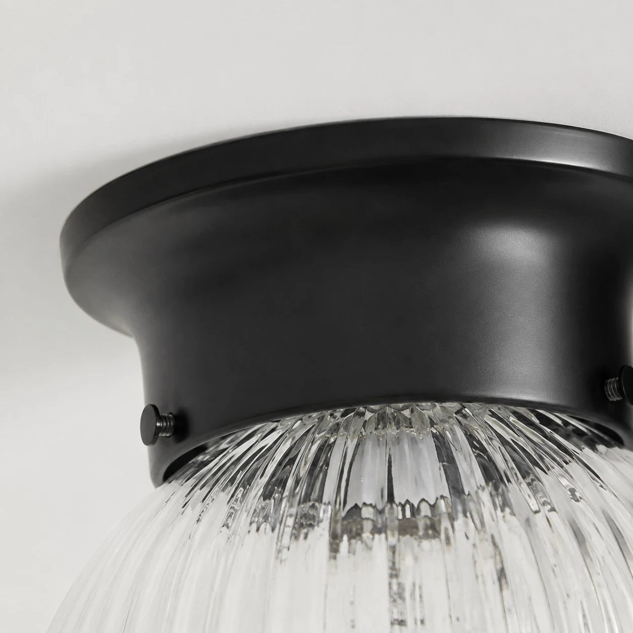 Close detail of black metal ceiling canopy and glass shade connection