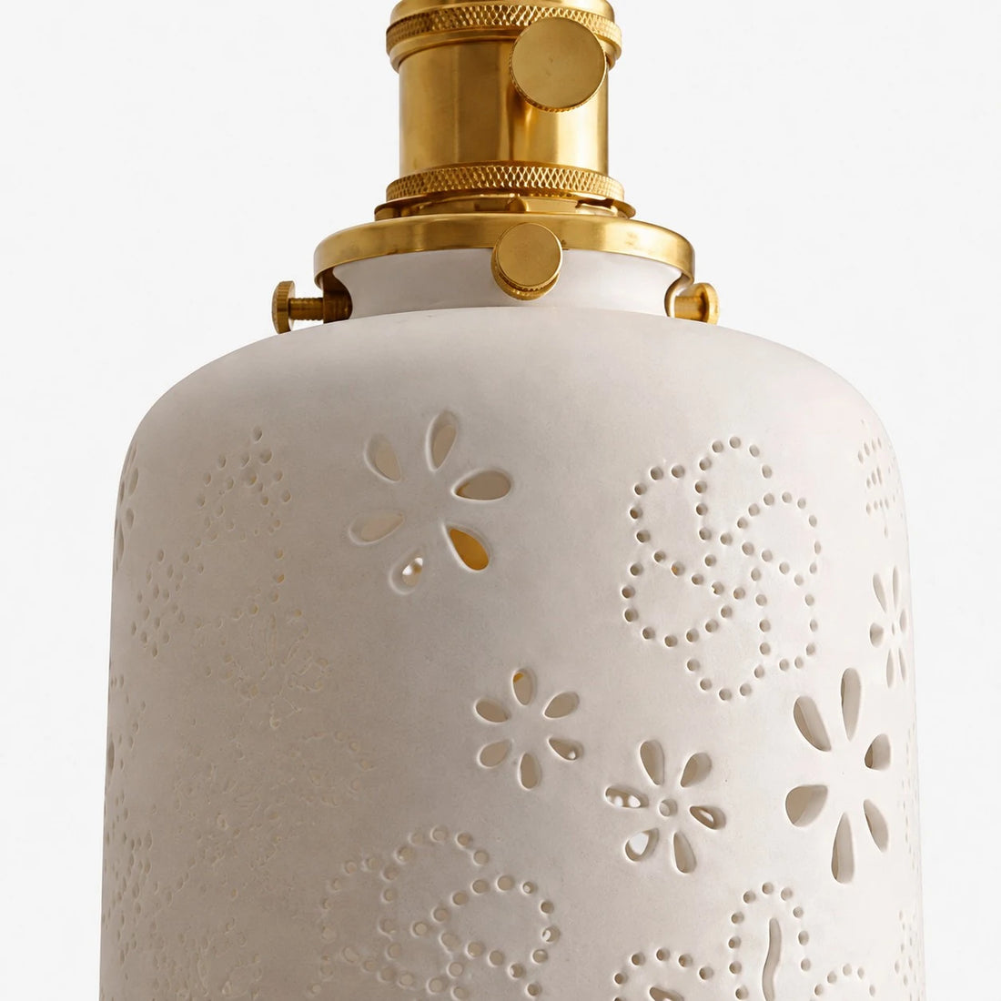 Close view of white ceramic shade with cutout floral pattern