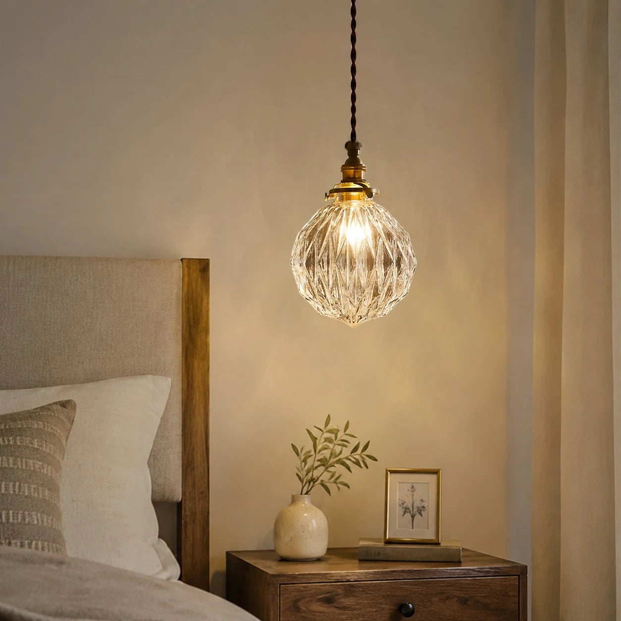 ribbed clear glass pendant light glowing over a bedside nightstand